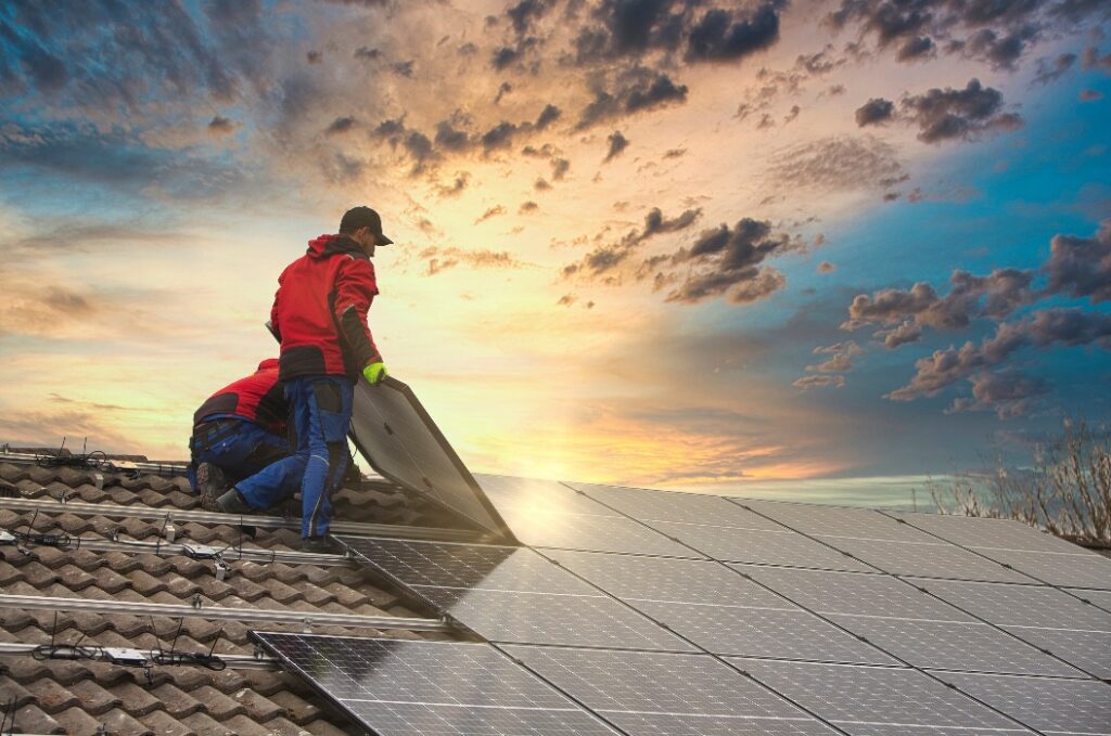 Montage einer Photovoltaikanlage. Solartechniker installiert Solarmodule auf dem Dach. Konzept für alternative, umweltfreundliche Energie.