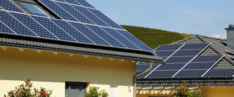 Dächer von Häusern mit Solarpaneelen unter klarem Himmel im Vorort.