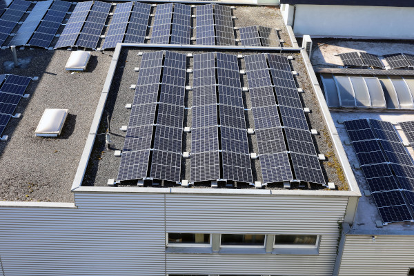 Mehrere Solarpanels sind auf einem flachen, grauen Industriedach montiert