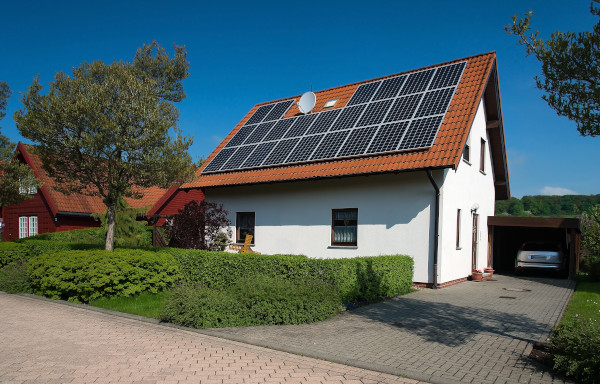 Ein modernes weißes Einfamilienhaus in Köln mit roten Dachziegeln und Solarpanels auf dem Dach