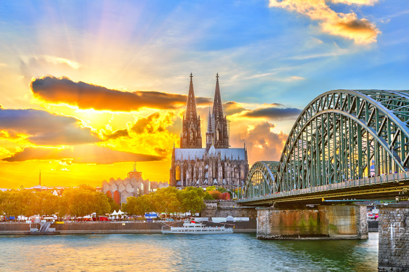 Der Kölner Dom im Sonnenuntergang mit dramatisch leuchtendem Himmel und Hohenzollernbrücke