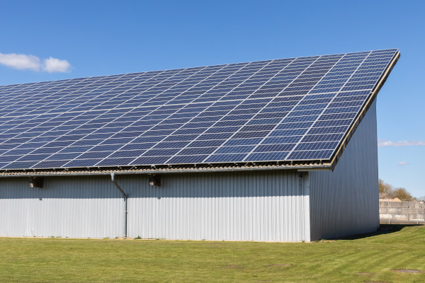 Ein großes Gewerbegebäude mit blauen Solarpanels unter klarem Himmel