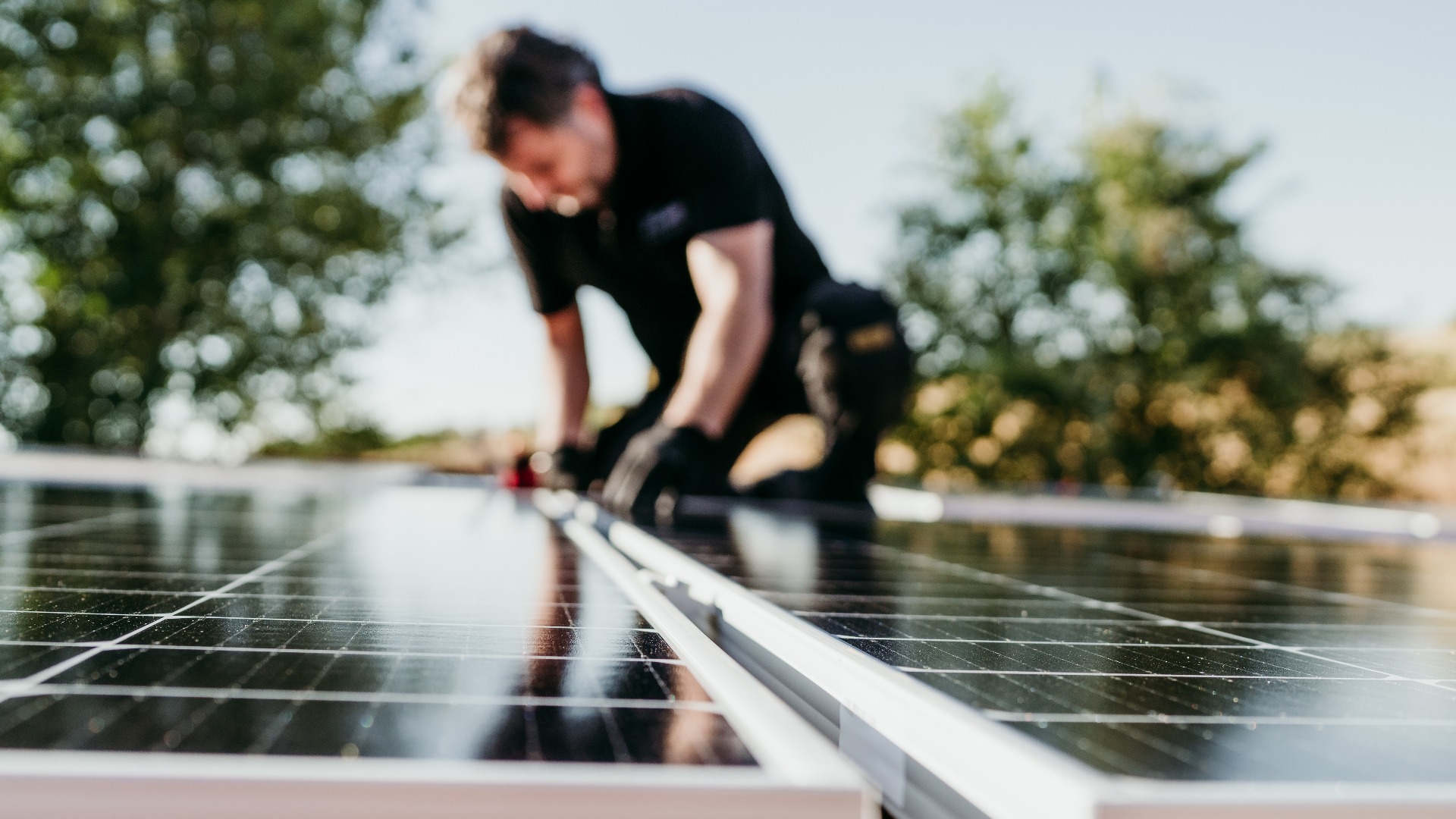mature Technician man assembling solar panels on house roof for self consumption energy. Renewable energies and green energy concept. focus on foreground